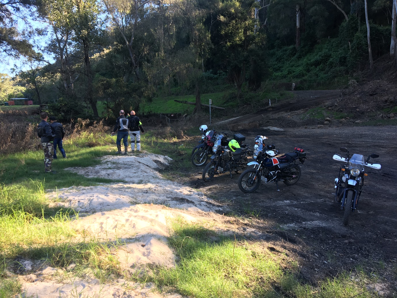 A group of people standing next to motorcycles on a dirt road

Description automatically generated with medium confidence